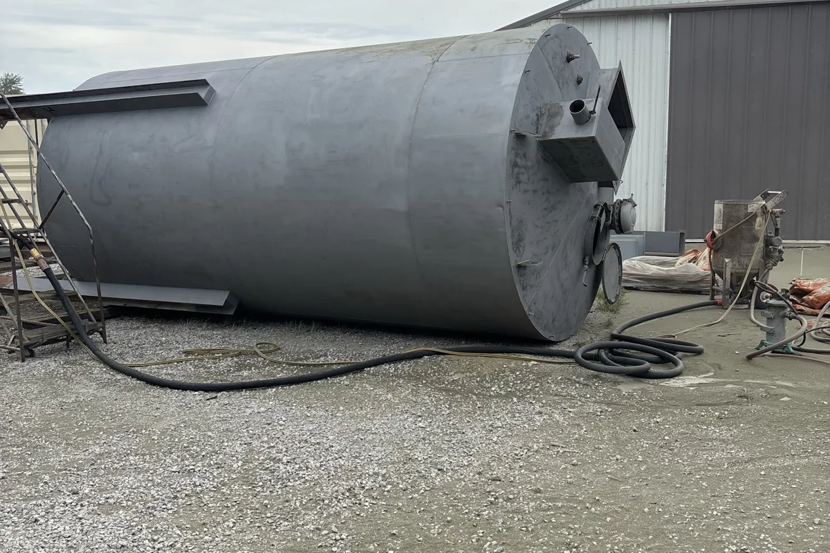 The same silo standing again after blasting, uniform bare steel